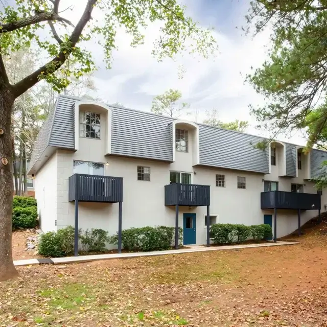 Apartment townhome exterior with private balconies and wooded surroundings at Elea Apartments in Marietta, GA