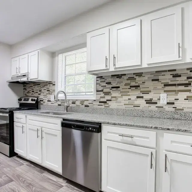 Renovated kitchen with white cabinets, tile backsplash, and stainless steel appliances at Elea Apartments in Marietta, GA