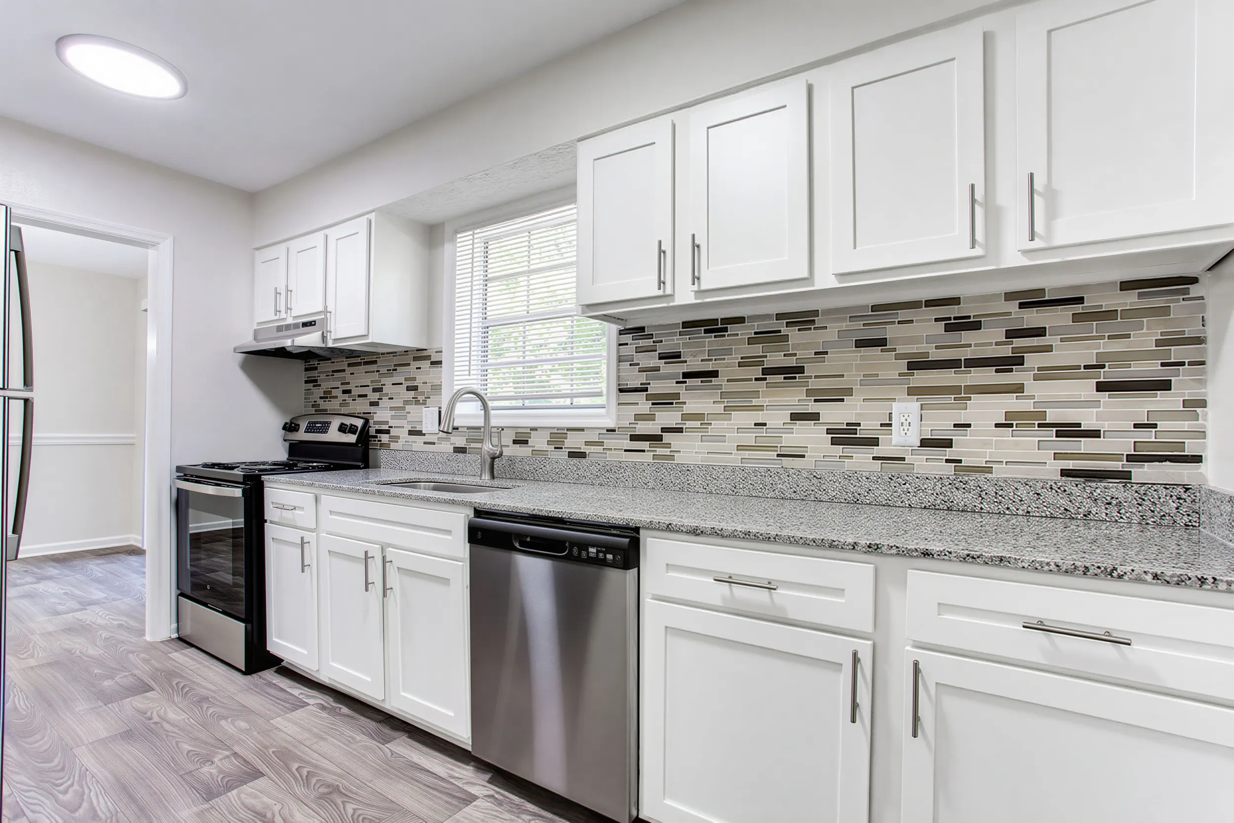 Renovated kitchen with white cabinets, tile backsplash, and stainless steel appliances at Elea Apartments in Marietta, GA