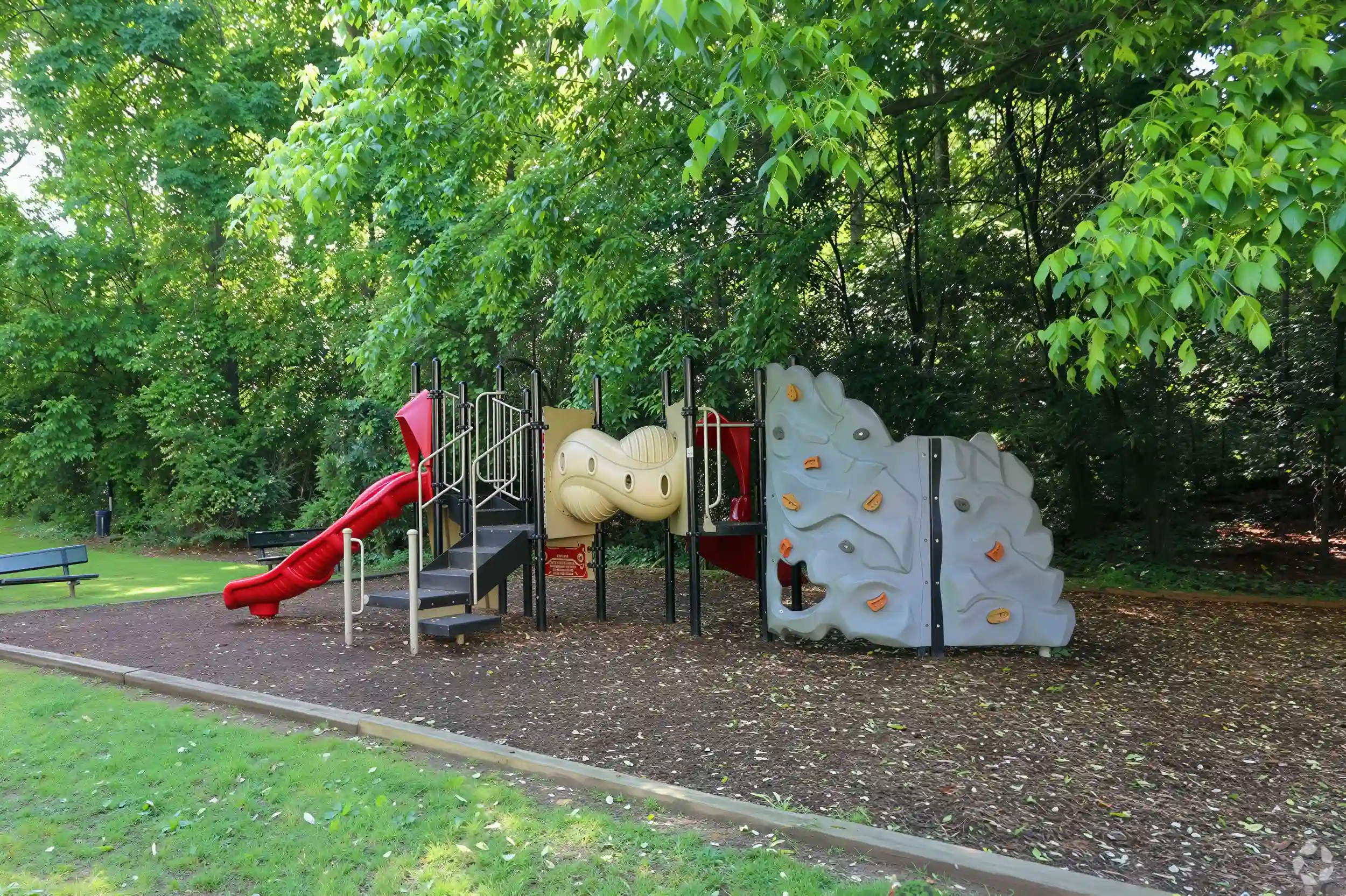Community playground surrounded by mature trees at Elea Apartments in Marietta, GA